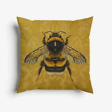 Sierkussen met een gedetailleerde gouden hommel op een achtergrond van warme tinten
